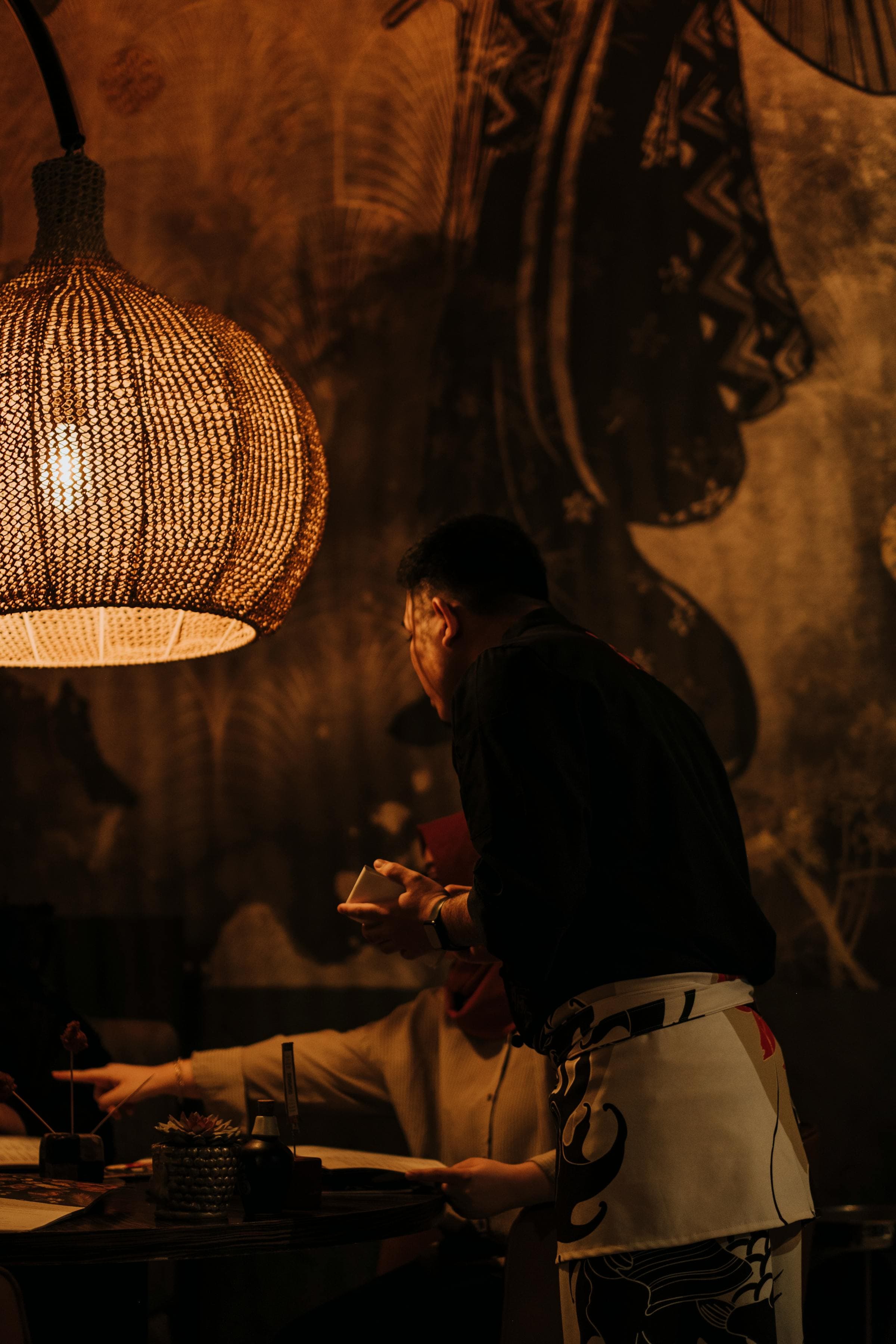 A server attending guests in a warmly lit dining room during evening service
